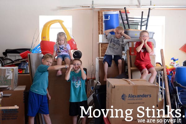 Five little kids making silly faces surrounded by moving boxes. 