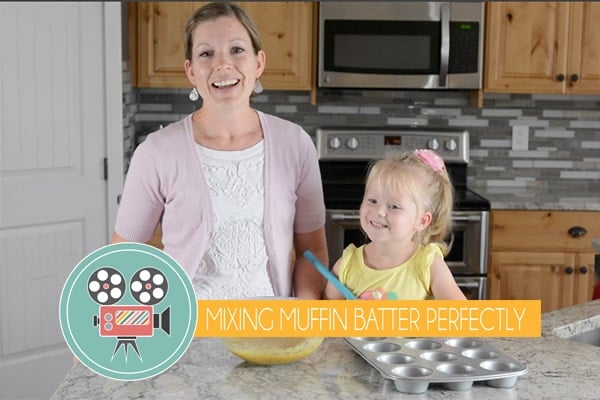 A mother and daughter standing in the kitchen together making muffins.