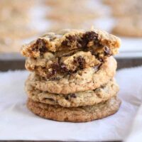 Stack of soft and chewy oatmeal chocolate chip coconut cookies with the top one broken in half.