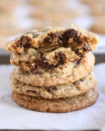 Stack of soft and chewy oatmeal chocolate chip coconut cookies with the top one broken in half.