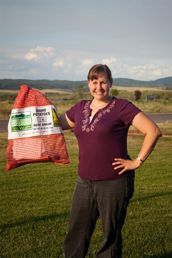 A woman holding a sack of potatoes.