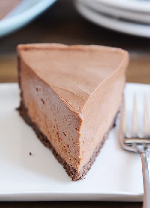 A slice of chocolate cheesecake with chocolate crust on a white plate.
