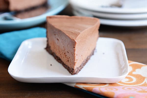 A slice of chocolate cheesecake with a chocolate crust on a white plate.