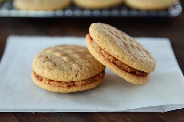 Two homemade peanut butter filled nutter butter cookies on a piece of parchment paper.