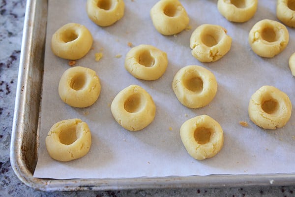 A cookie sheet of uncooked shortbread cookies with imprints in the middle.