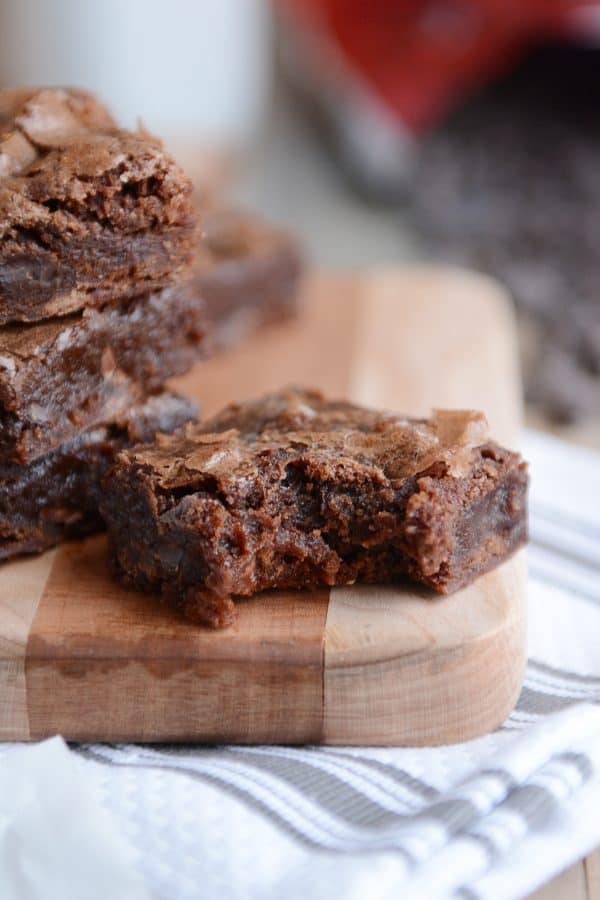 A stack of brownies with one in front with a bite taken out.