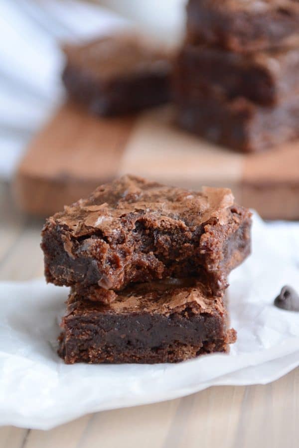 A stack of brownies with a bite taken out of the top one. 