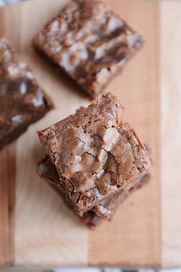 A stack of chocolate brownies on a wooden cutting board. 