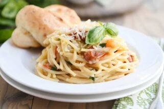 One pot creamy tomato basil pasta on white plate with parmesan breadstick.