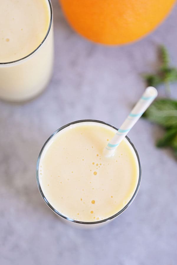 Top view of an orange smoothie in a glass cup with a straw. 