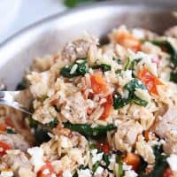 Mediterranean orzo skillet with serving spoon.