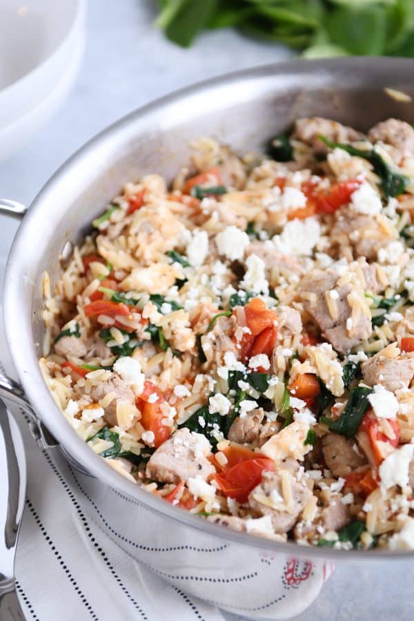 Stainless pan filled with Mediterranean orzo skillet with pork. 