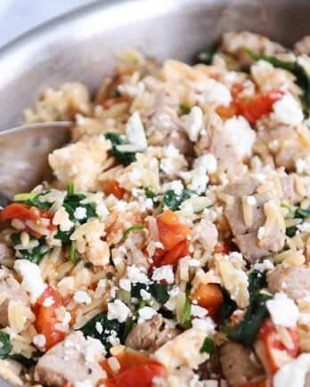 Stainless pan filled with Mediterranean orzo skillet with pork.