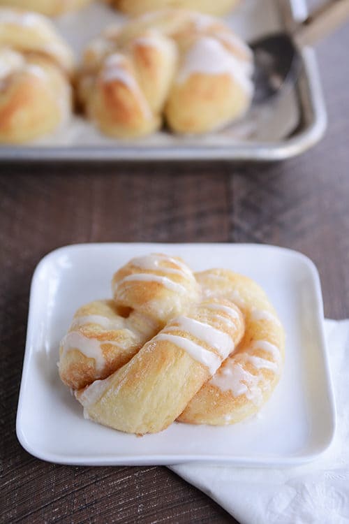 A frosting glazed cinnamon and sugar twist on a white plate. 