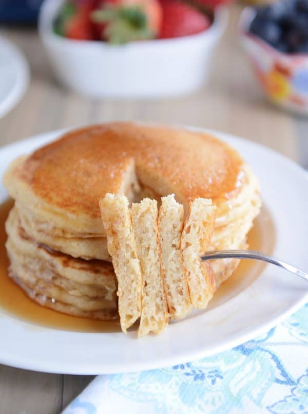 A stack of pancakes with a fork taking a bite out. 