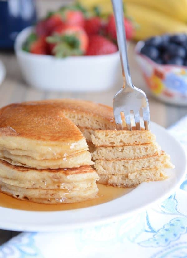 A fork taking a big bite out of a stack of pancakes. 