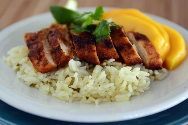 Slices of grilled chicken and sliced mango over a bed of rice.