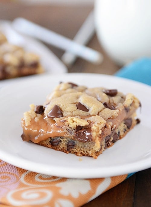 A chocolate chip peanut butter caramel cookie bar on a white plate.