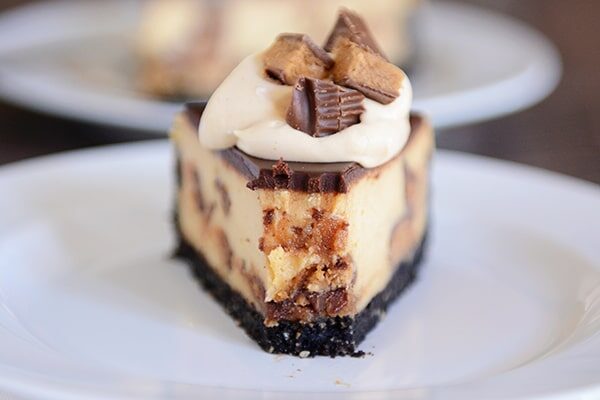 A slice of cookie crust peanut butter cup cheesecake with a bite taken out.