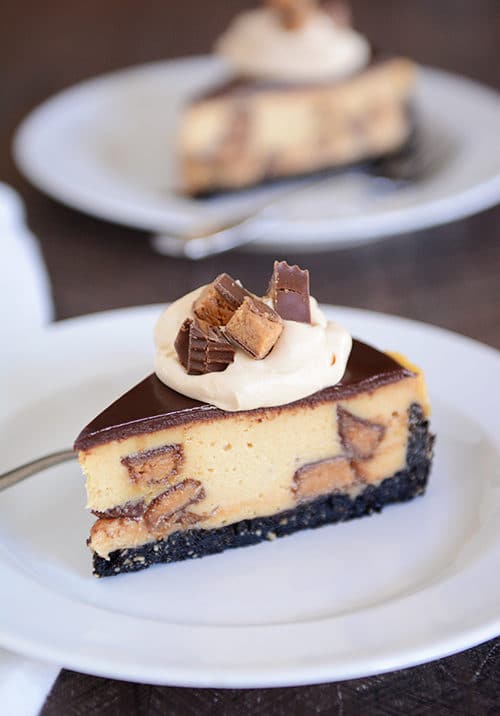 A slice of cookie crust peanut butter cup cheesecake on a white plate.