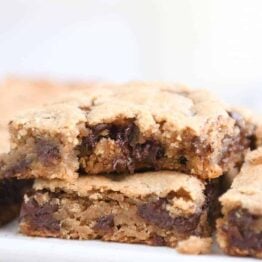 Bite taken out of peanut butter chocolate chip bar on white platter.