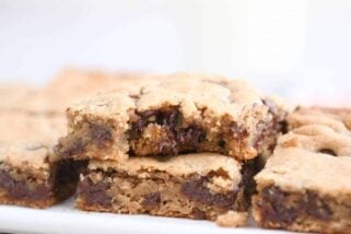 Bite taken out of peanut butter chocolate chip bar on white platter.