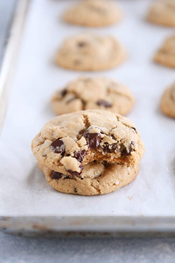 Two peanut butter oatmeal chocolate chip cookies on parchment paper with bite taken out of top cookie.