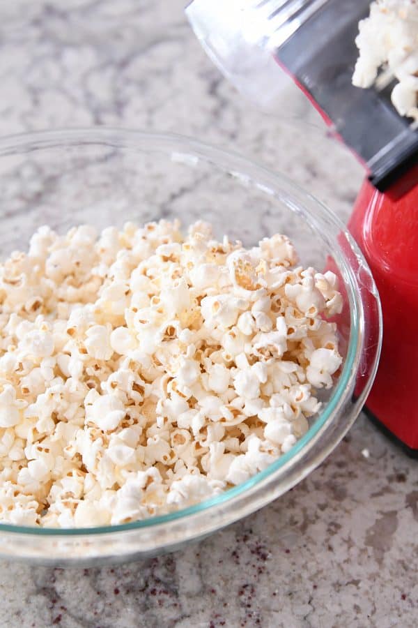 Air popper popping popcorn into glass bowl.