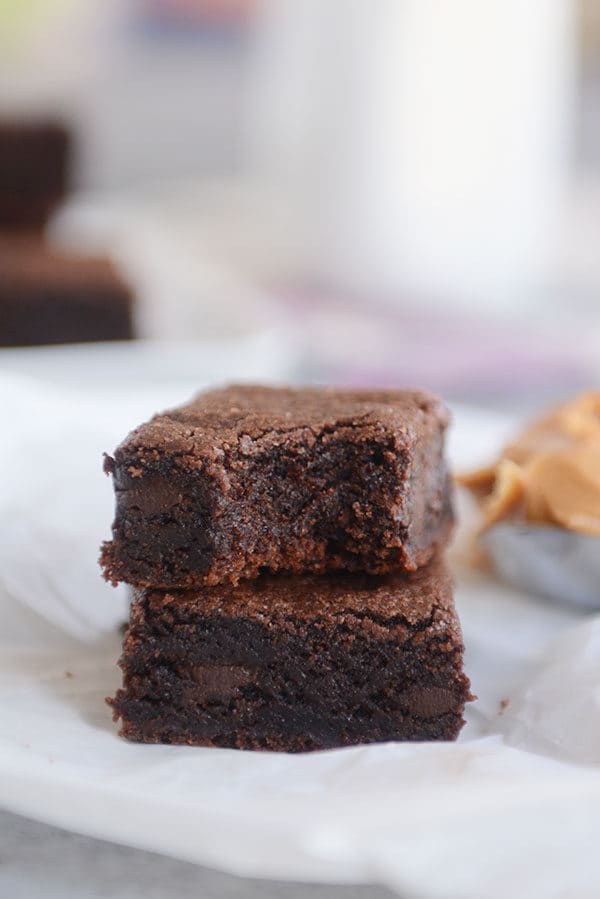 Two chocolate brownies stacked on top of each other, with a bite taken out of the top one.