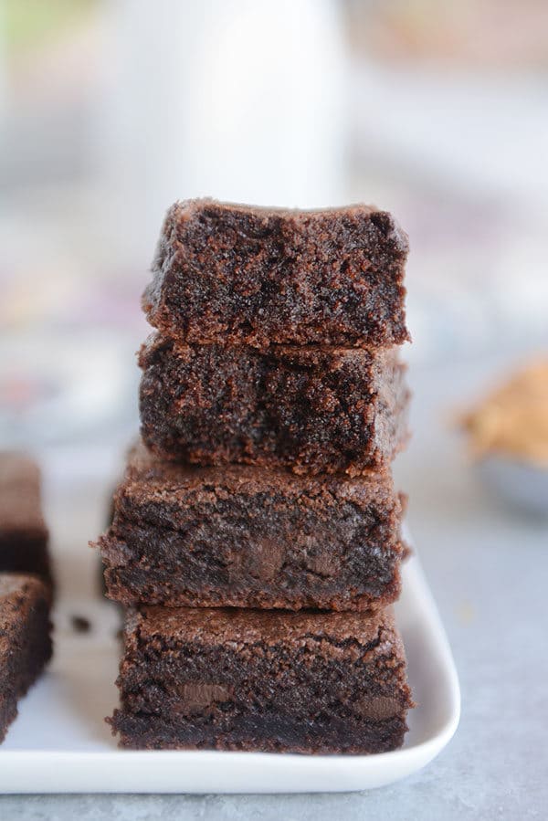 Four brownies stacked on top of each other on a white plate.