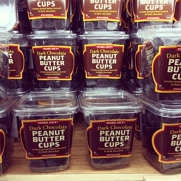 A big stack of Trader Joe's containers of dark chocolate peanut butter cups. 