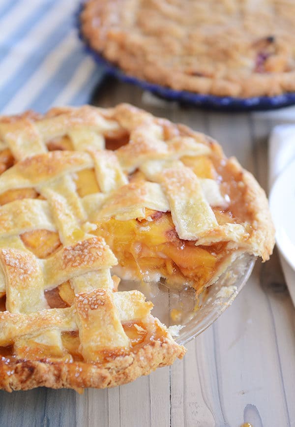 A lattice-topped fresh peach pie with a slice taken out. 