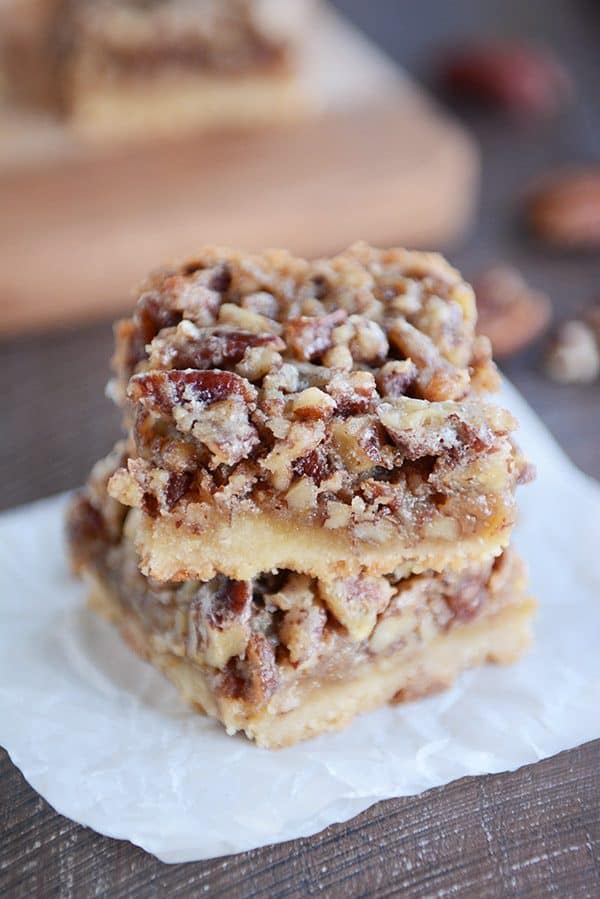 two pecan pie bars stacked on top of each other on a square of parchment 