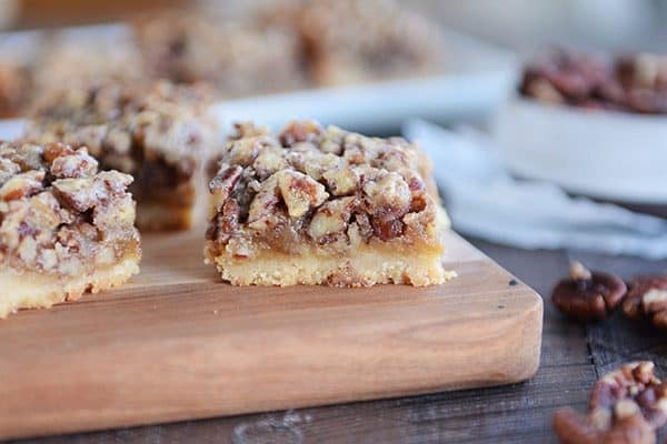 Cut up pecan pie bars on a wooden cutting board.