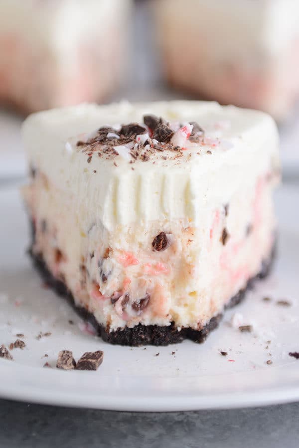 Front view of a slice of white chocolate peppermint cheesecake with a bite taken out.