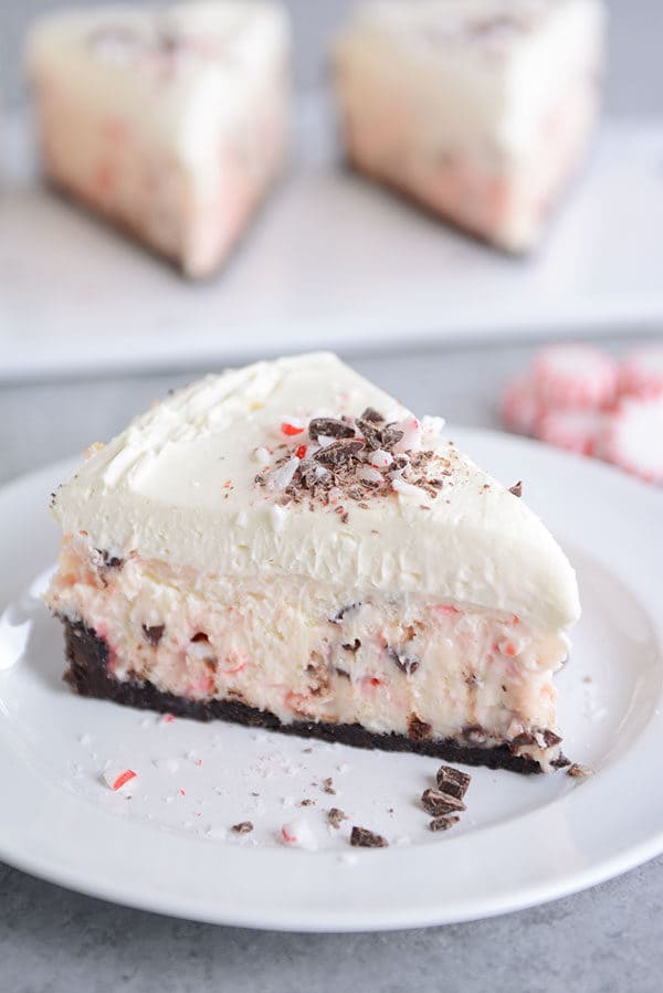 A slice of layered white chocolate peppermint cheesecake on a white plate.