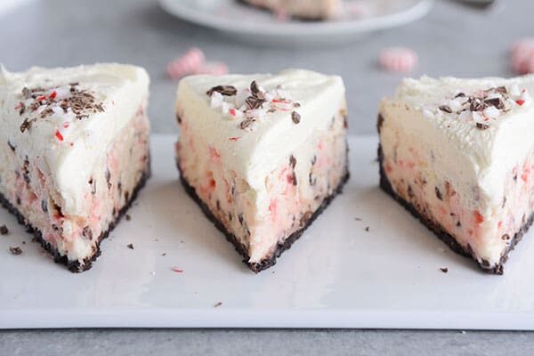 Three slices of peppermint white chocolate cheesecake lined up on a white platter.