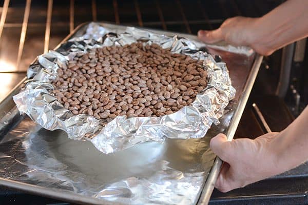 A pie crust filled with tinfoil and dry pinto beans going into the oven.
