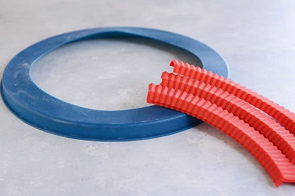 A blue pie crust cover ring, and red crimped pie crust covers.