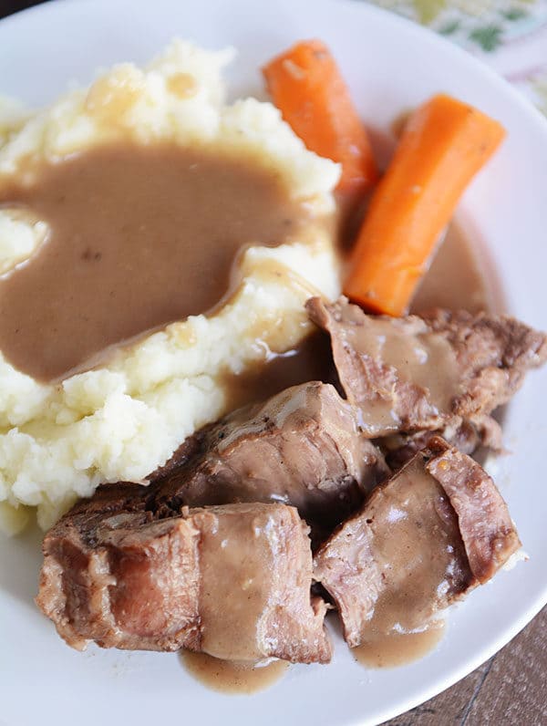 Top view of mashed potatoes, carrots, and roast covered with gravy. 