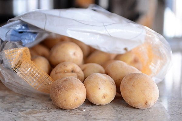 Sack of gold potatoes spilling onto a kitchen counter.