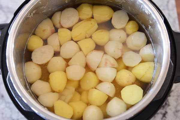 Cut up potatoes immersed in water in an Instant Pot, ready to cook. 