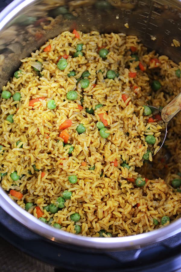 An Instant Pot bowl full of yellow-tinted rice with peas and carrots throughout.