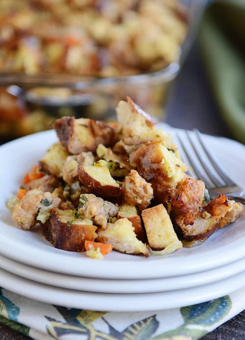 A white plate full of pretzel roll sausage stuffing with a fork on the side. 