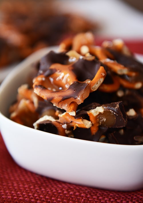 A white bowl full of chocolate caramel pretzel bark. 