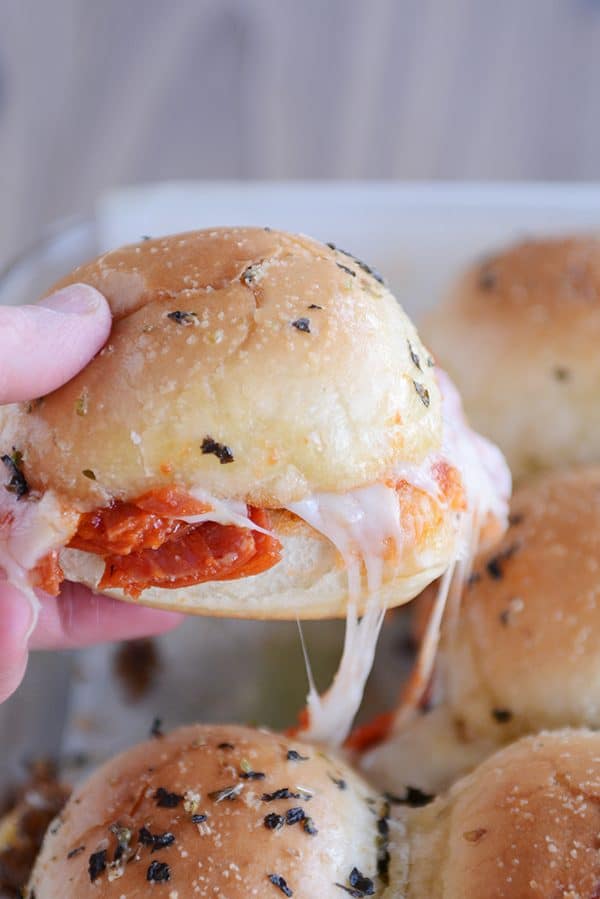 A hand holding a cheesy pull-apart pizza slider.