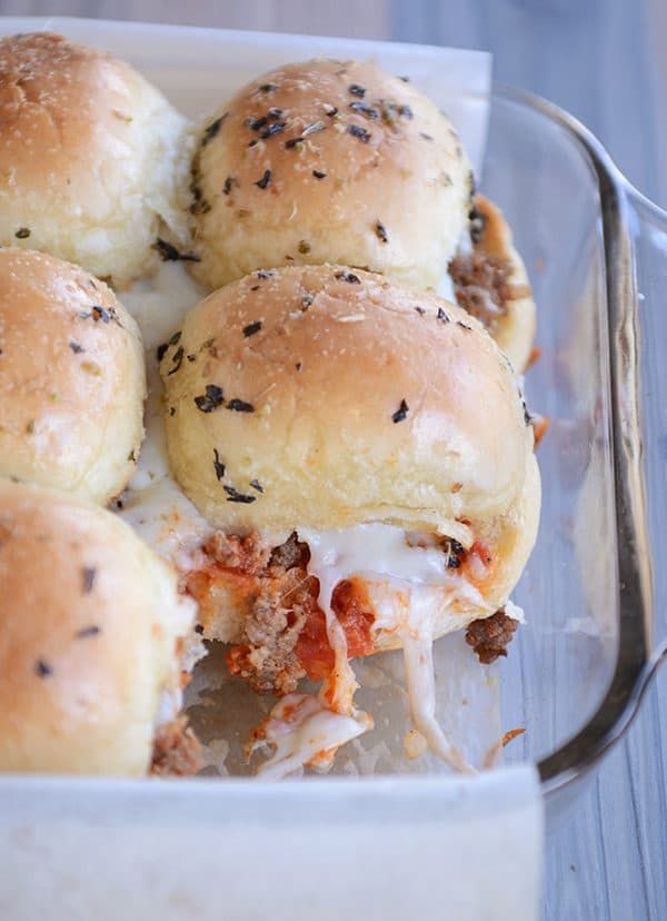 A glass dish of cheesy pepperoni pizza sliders. 