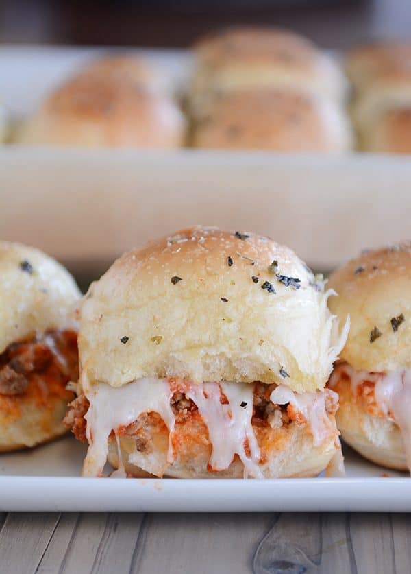 Cheesy pull-apart pizza sliders lined up on a white tray.