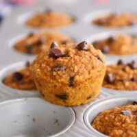 Easy pumpkin blender muffins in muffin tin with one muffin sitting on top.