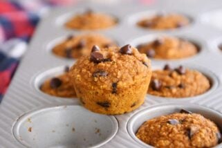 Easy pumpkin blender muffins in muffin tin with one muffin sitting on top.